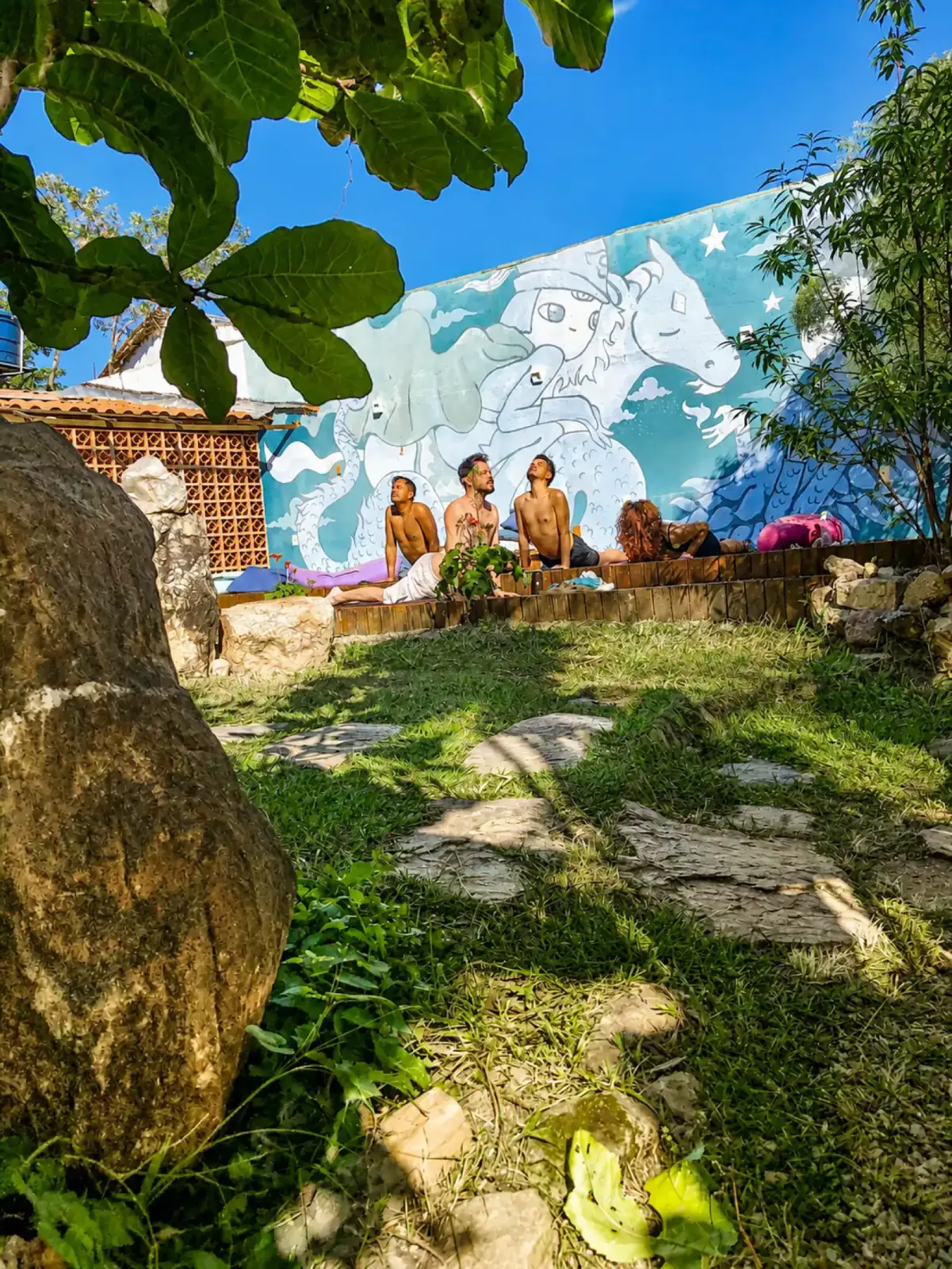 Hóspedes reunidos no jardim, em frente ao mural da Shanti Pousada