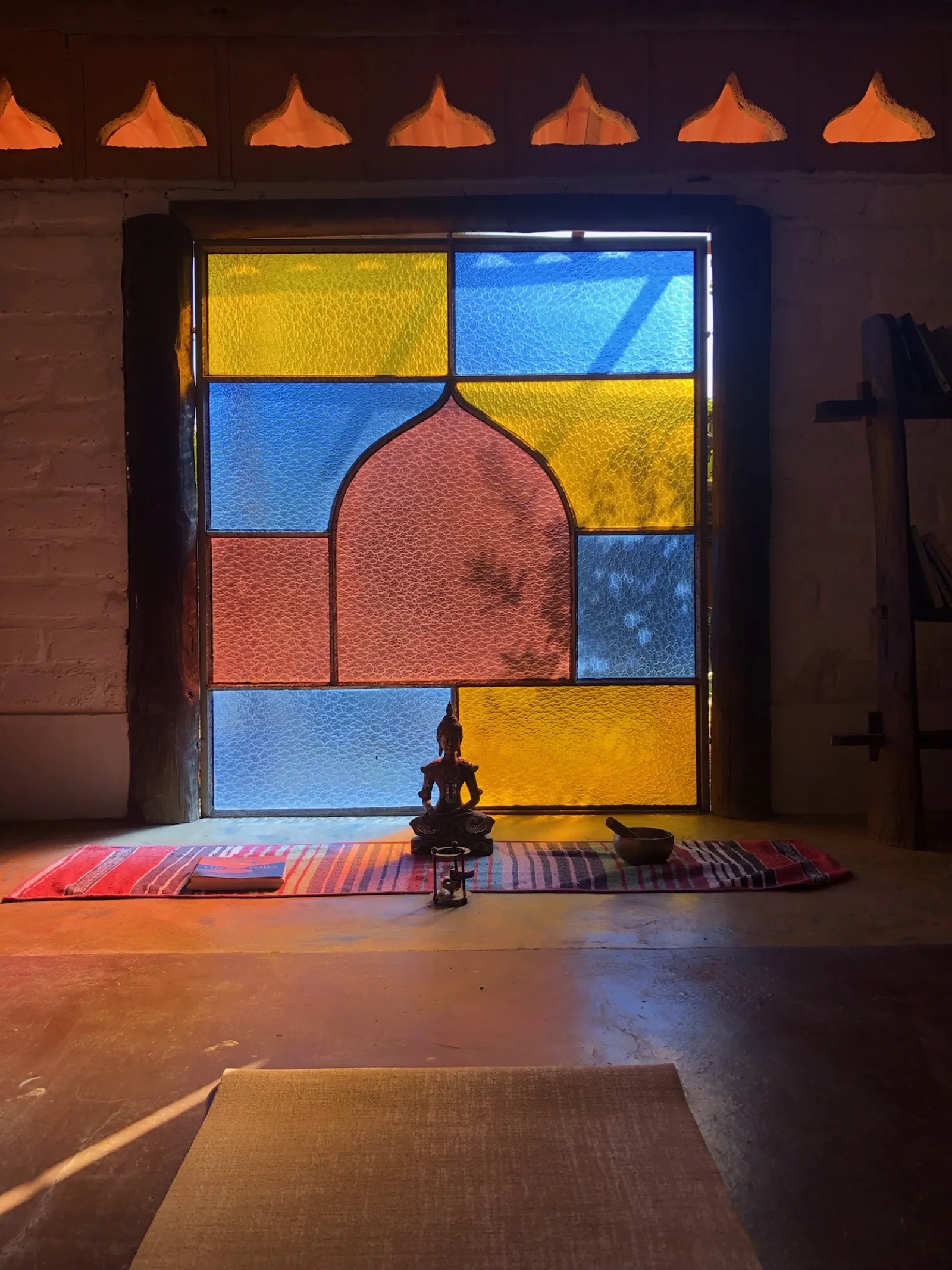 Cantinho de meditação com vitrais e imagem de Buda, bioconstrução em adobe da Shanti Pousada, São Jorge